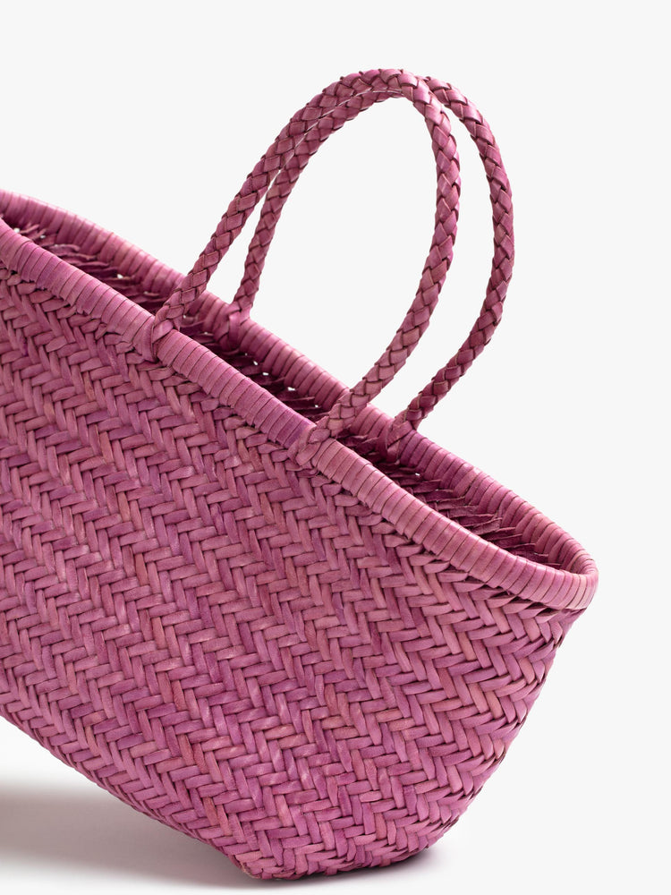 Close up view of a pink, woven leather bag.
