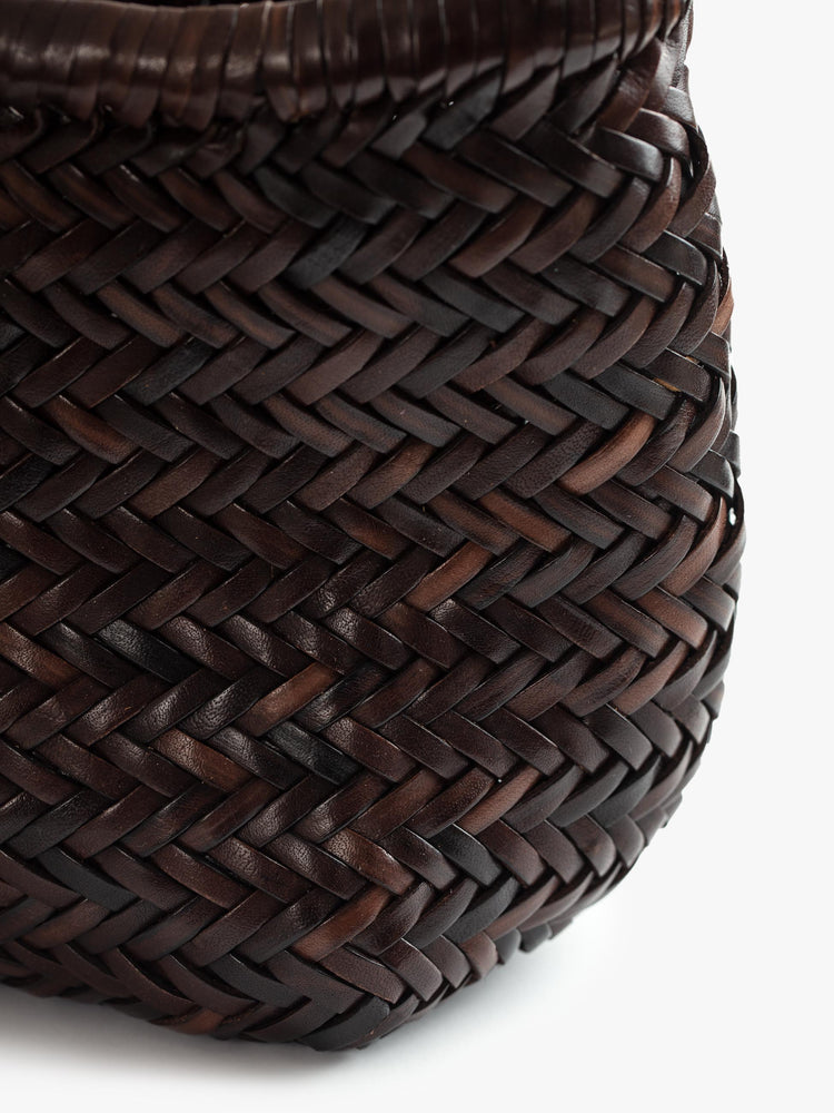 Close up view of a dark brown, woven leather bag.