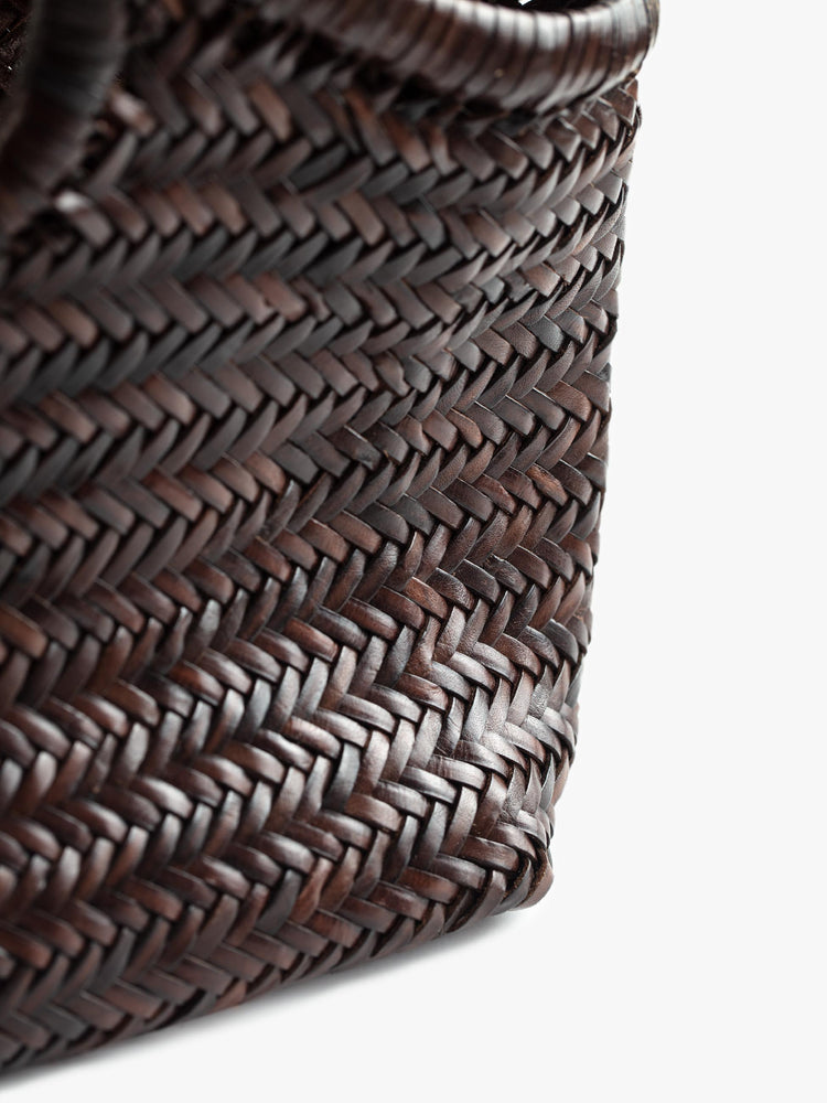 Close up view of a dark brown, woven leather bag.