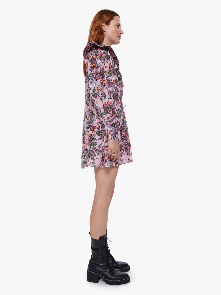 Side view of a womens pink floral dress featuring long sleeves and a wide ruffle at the hem.