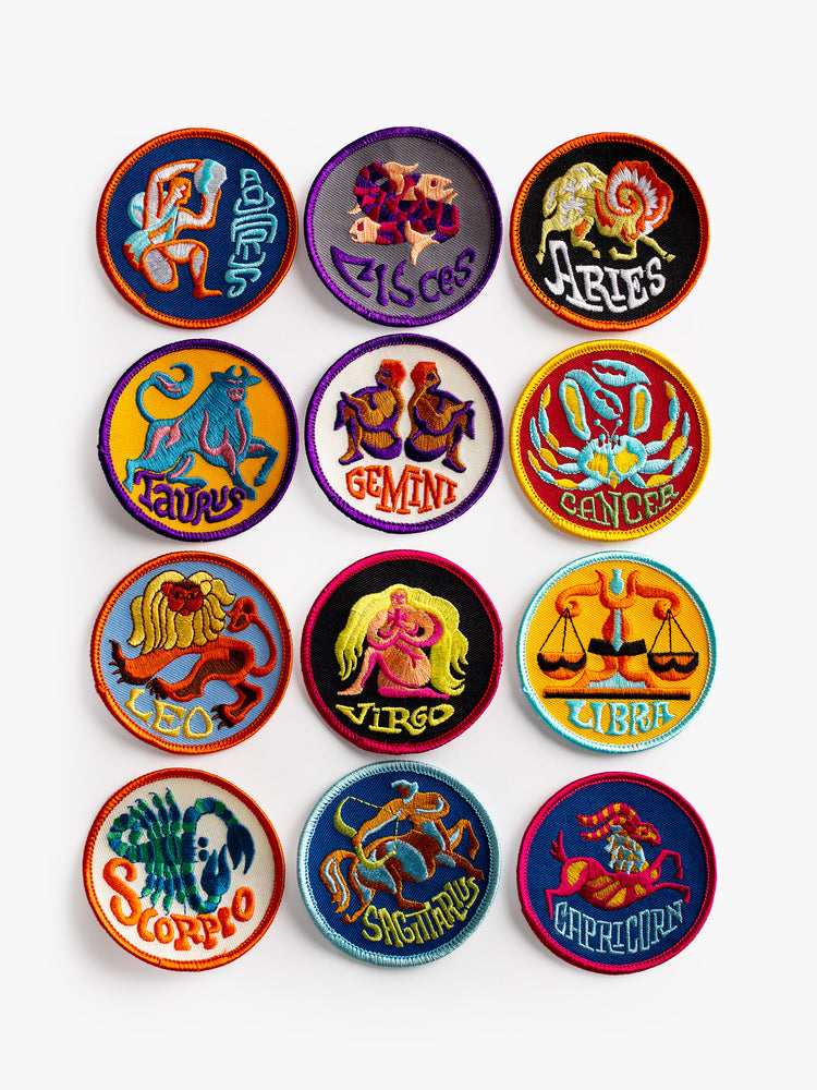 A top front view of 12 round, embroidered patches featuring the 12 astrological signs