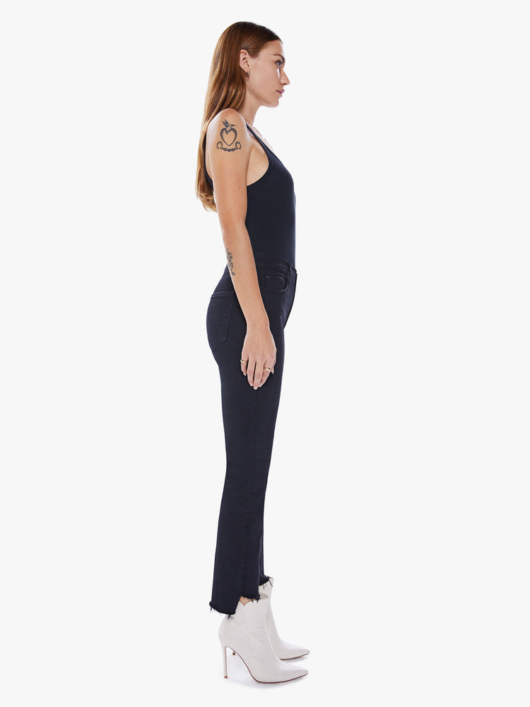 Side view of a womens black jean featuring a mid rise, straight leg, and an ankle length crop step hem.