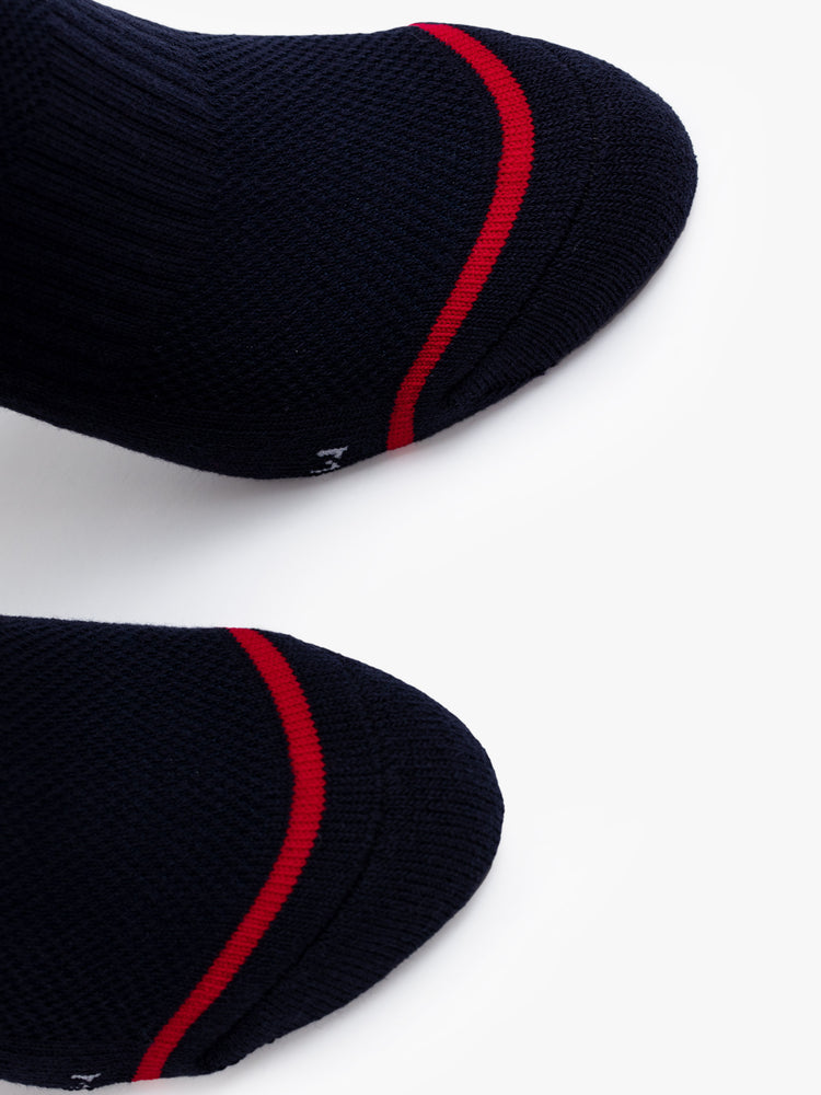 Close up view of a pair of black socks featuring a red pattern and text in white.