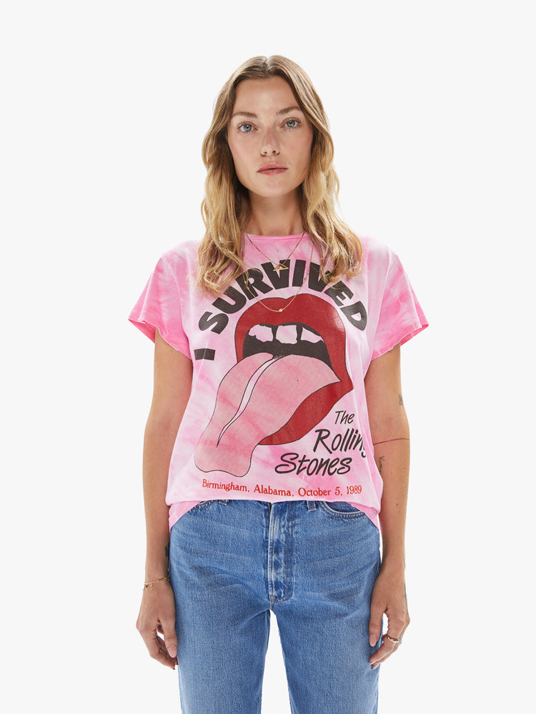 Front view of a woman wearing a pink tie dye crew neck tee featuring a large The Rolling Stones concert graphic.