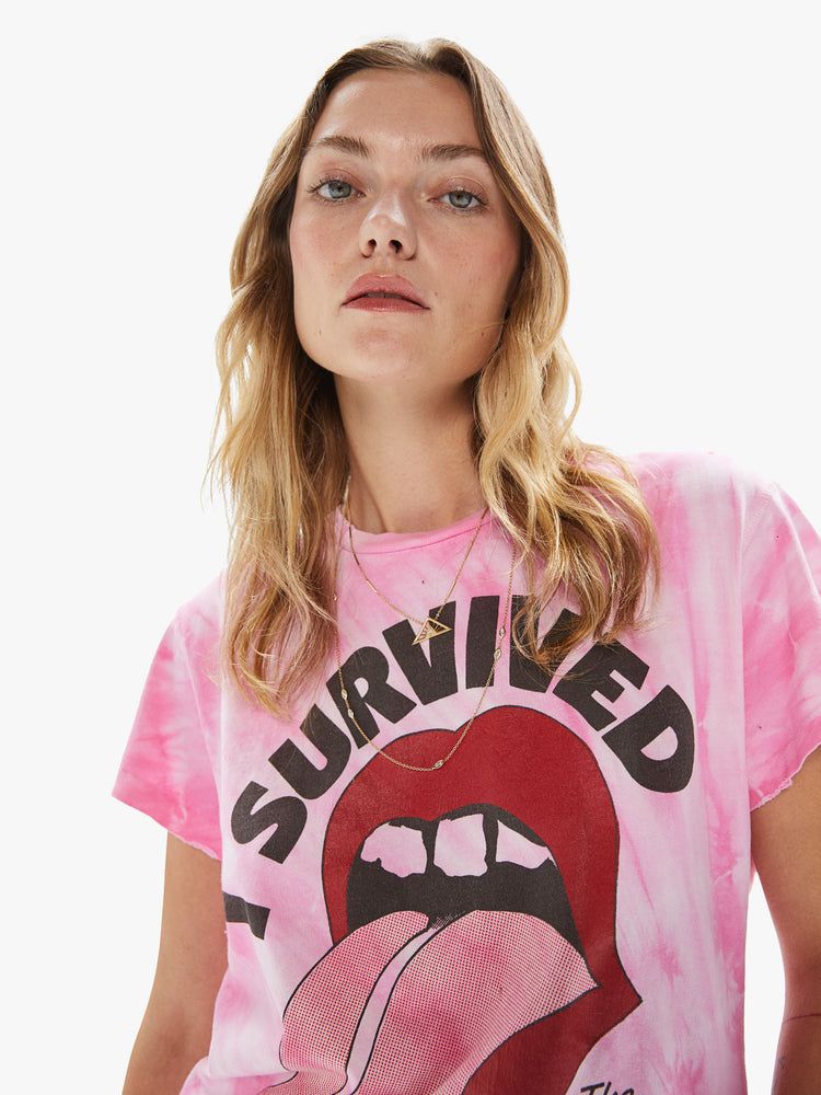 Front close up view of a woman wearing a pink tie dye crew neck tee featuring a large The Rolling Stones concert graphic.