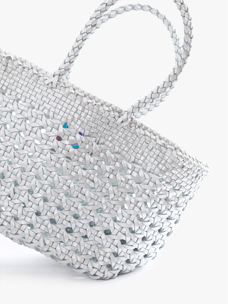Close up view of a womens silver, leather woven bag.