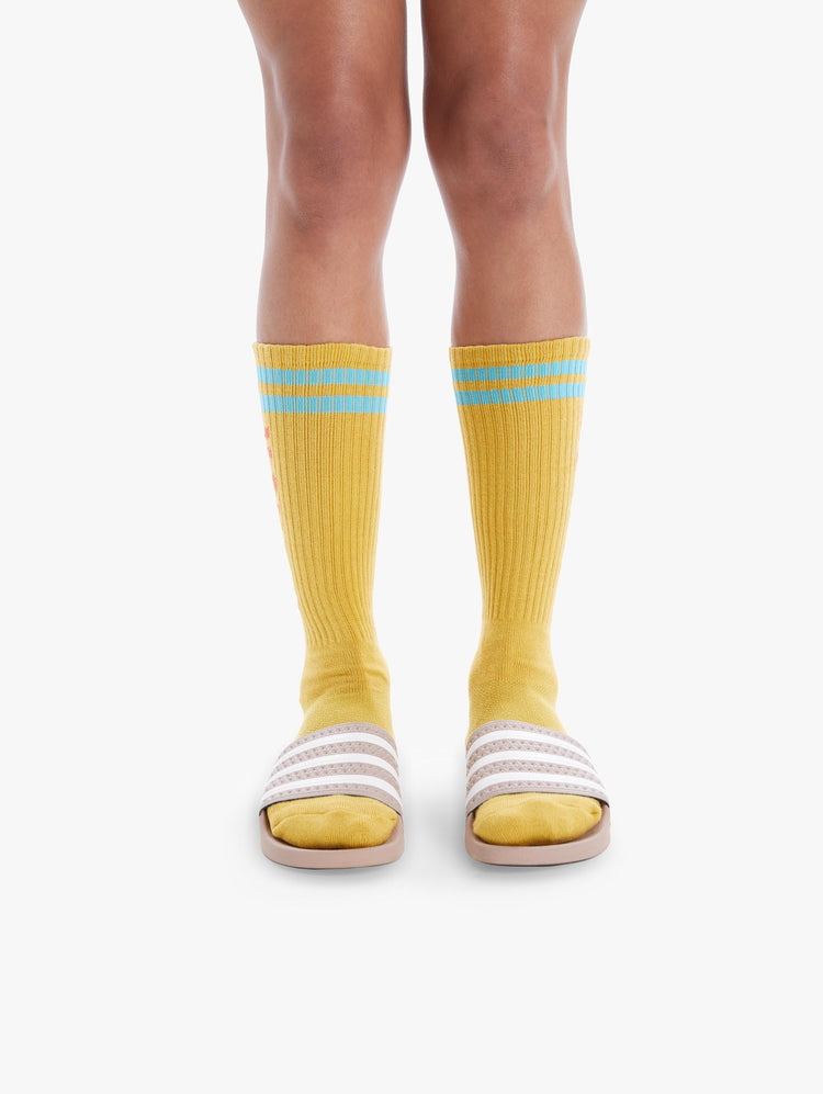 FRONT VIEW WOMEN'S YELLOW TALL SOCK WITH LIHGT BLUE STRIPING AT THE TOP ORANGE MOVE IT SIDE LETTERING AND BLACK BOTTOM LETTERING