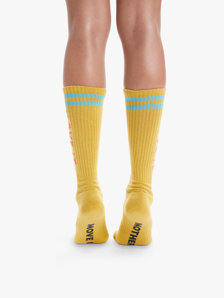 BACK  VIEW WOMEN'S YELLOW TALL SOCK WITH LIGHT BLUE STRIPING AT THE TOP ORANGE MOVE IT SIDE LETTERING AND BLACK BOTTOM LETTERING