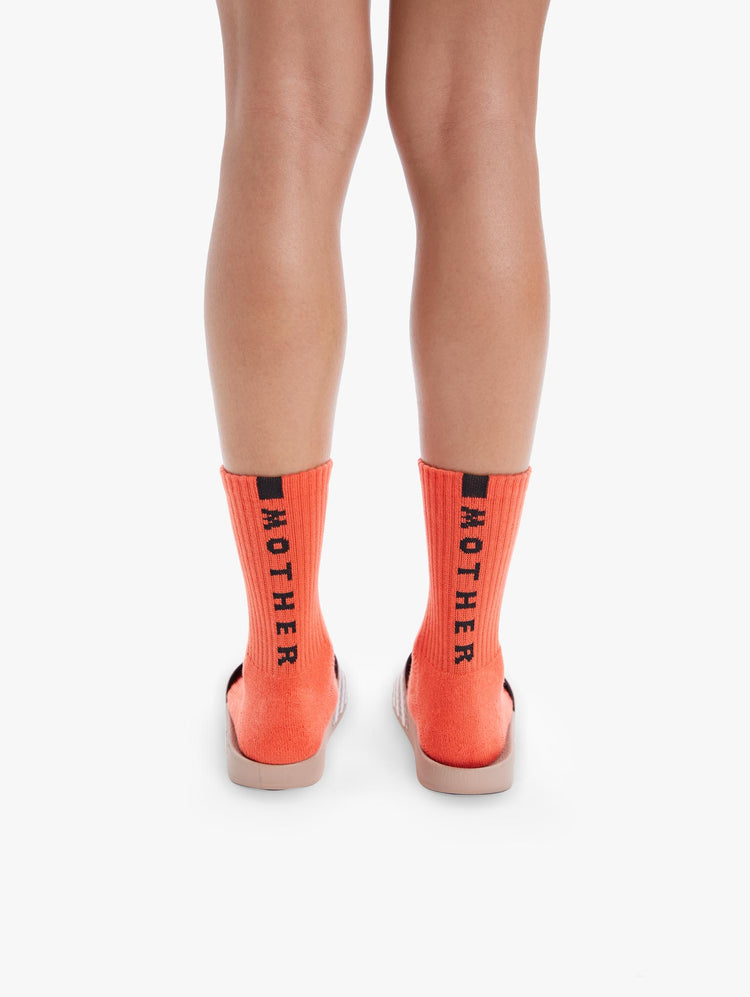 BACK VIEW WOMEN'S MID CALF LENGTH ORANGE SOCK WITH YELLOW SIDE MOVE IT LETTERING WITH BOTTOM BLACK MOTHER LETTERING