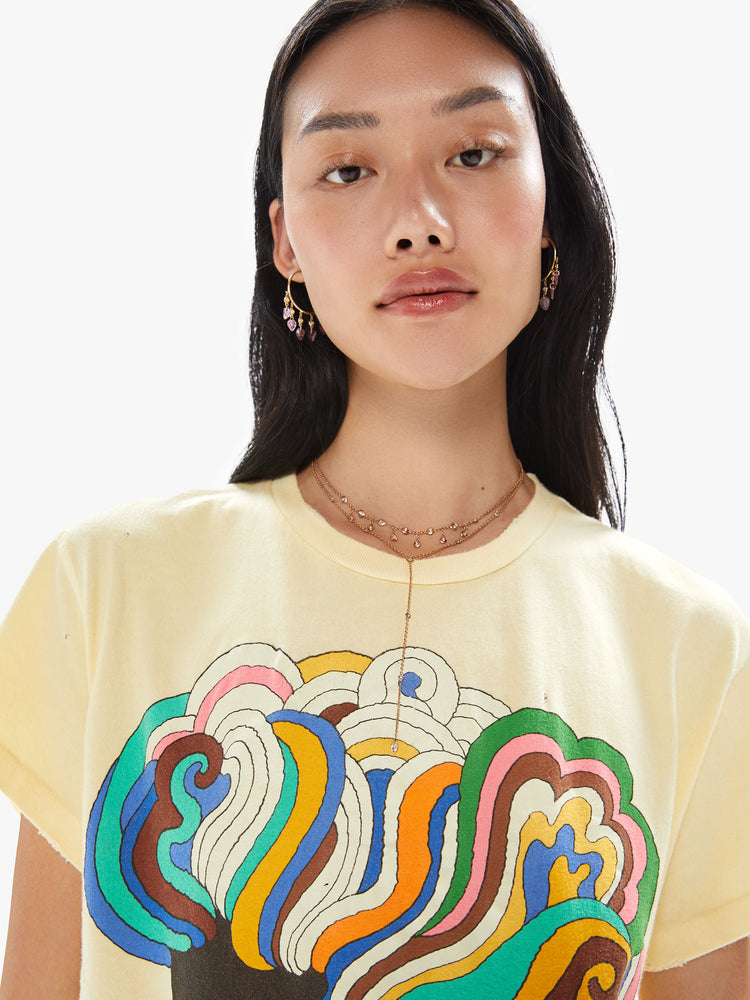 Close up view of a woman wearing a faded yellow crew neck tee with a large colorful Bob Dylan graphic.