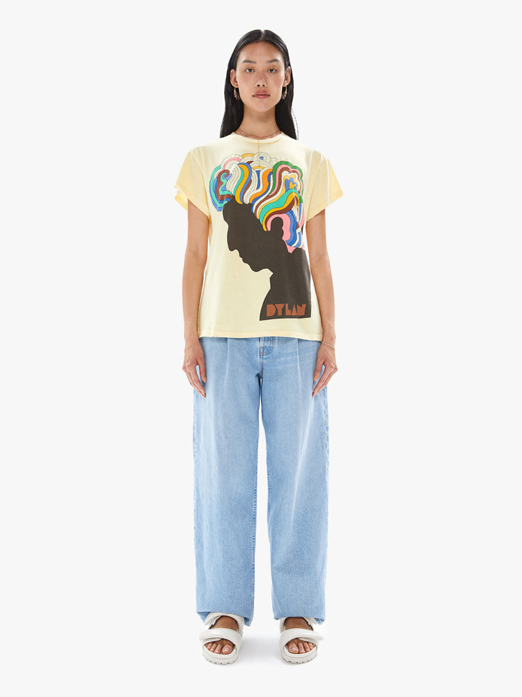 Front full body view of a woman wearing a faded yellow crew neck tee with a large colorful Bob Dylan graphic.