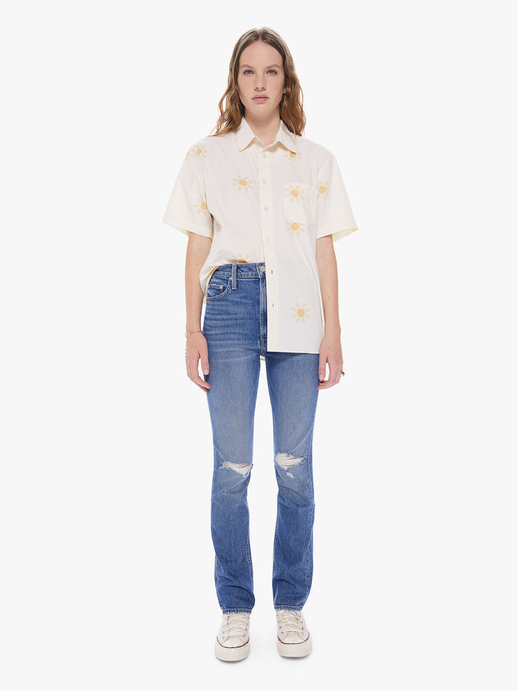 WOMEN Front full body view of a woman wearing a white, short sleeve collared shirt featuring a front pocket, a sun pattern, and a boxy oversized fit.