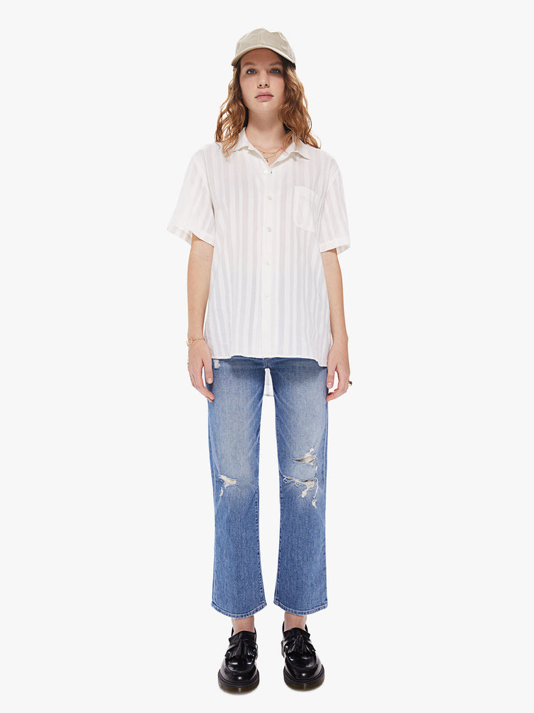 WOMEN Front full body view of a woman wearing a white, short sleeved collared shirt, featuring embroidered stripes, a front patch pocket, and a boxy oversized fit.