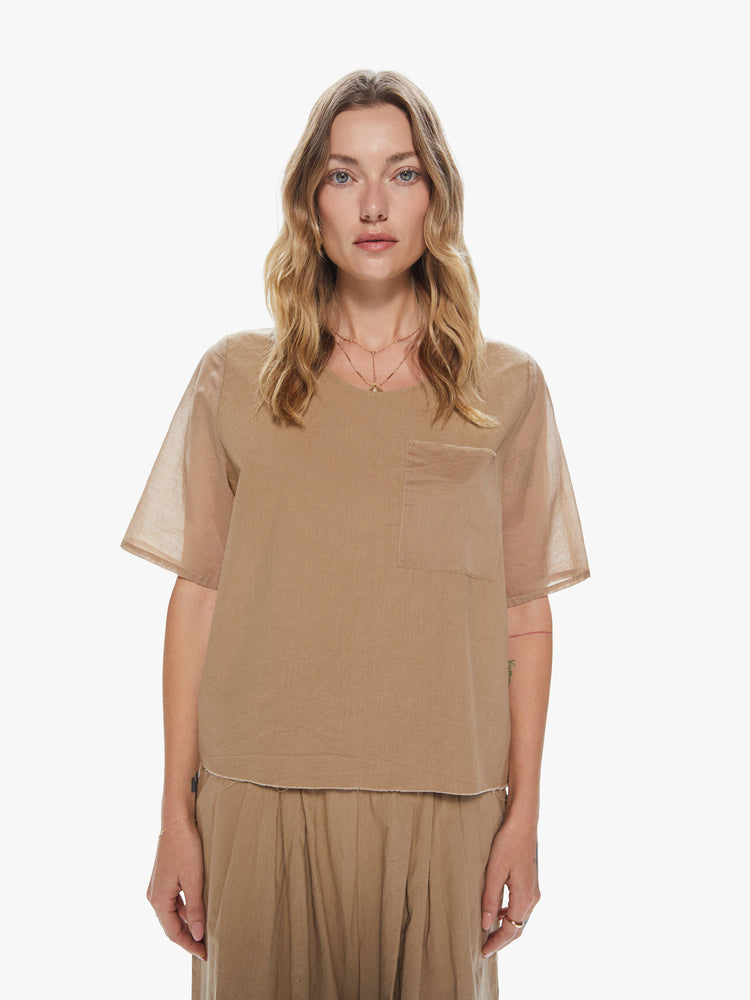 Front view of a woman wearing a khaki crew neck top featuring a chest pocket and sheer sleeves.