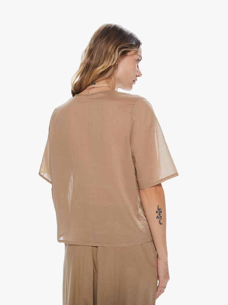 Back view of a woman wearing a khaki crew neck top featuring a chest pocket and sheer sleeves.