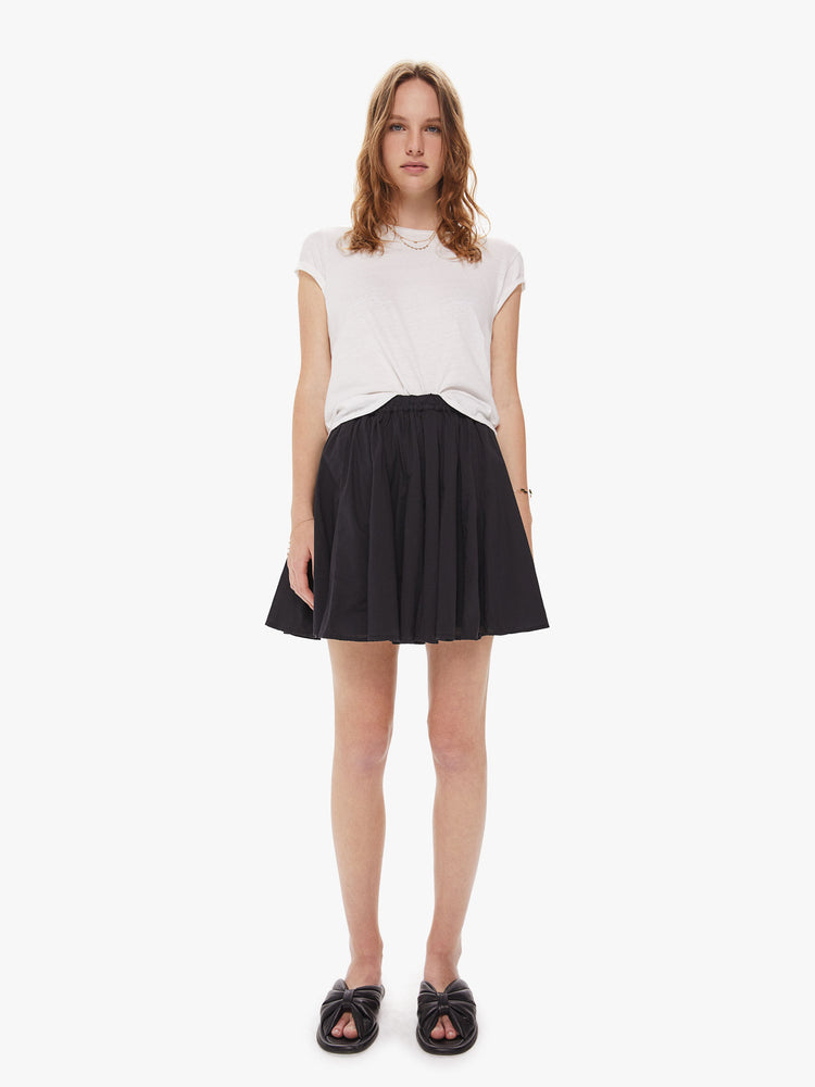 Front view of a woman wearing a black skirt, featuring a high elastic wiast and a short hem.