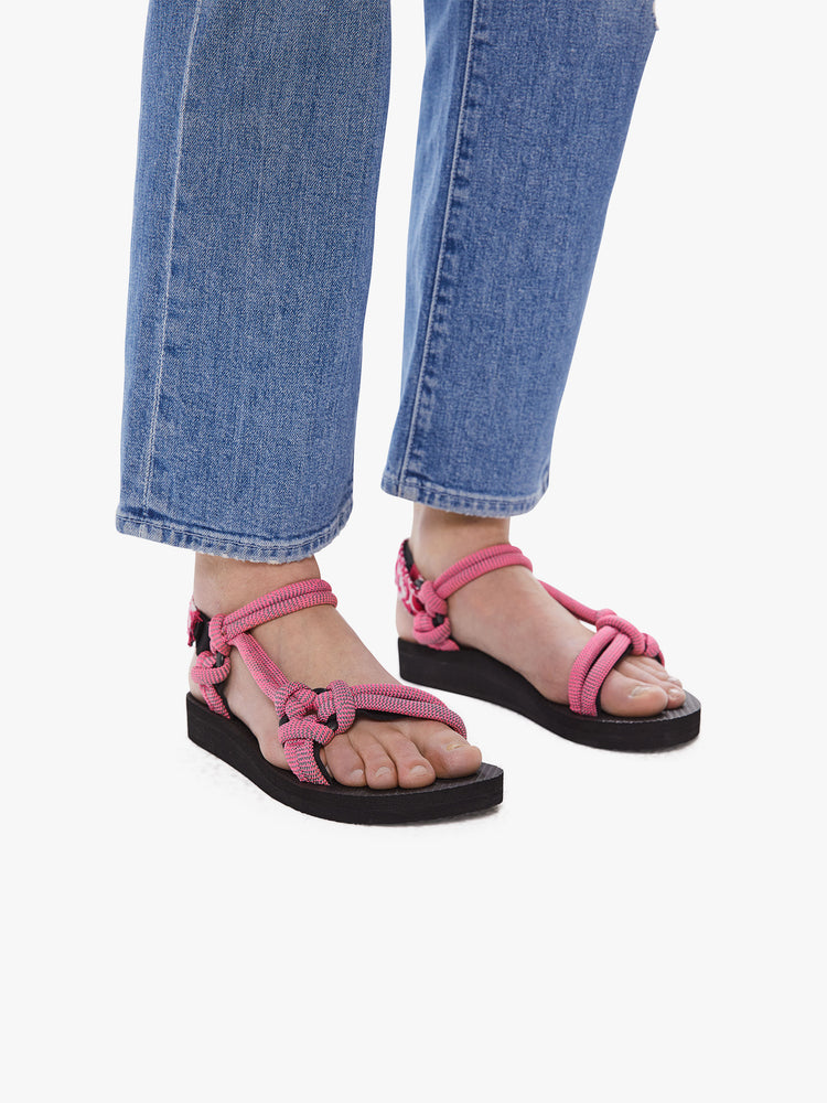 Side view of a woman wearing velcro sandals featuring a black foam sole and thick pink rope straps.