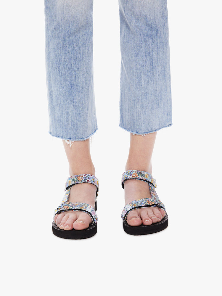 Front view of a woman wearing a pair of velcro sandals featuring a black foam sole and a pastel floral print.
