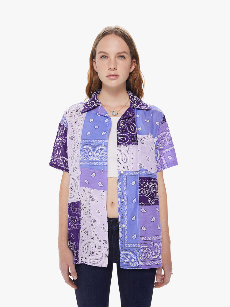 Front view of a woman wearing an oversized short sleeve button down shirt featuring purple bandana patchwork.
