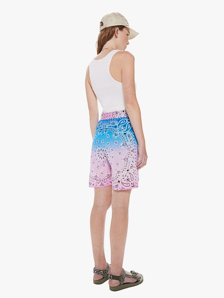 Back view of a woman wearing long shorts featuring a high elastic waist and a blue to pink ombre bandana print.
