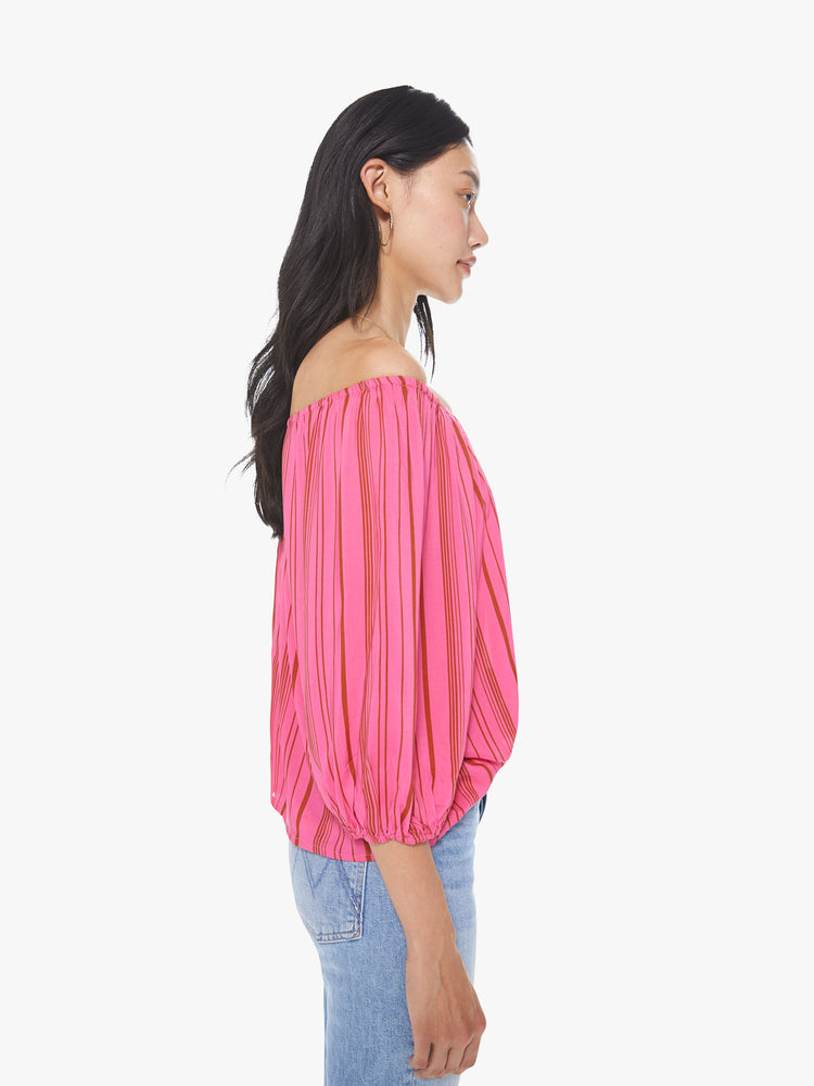 Side view of a women's bright pink off-shoulder blouse with red vertical stripes and 3/4 sleeves
