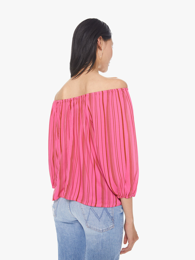 Back view of a women's bright pink off-shoulder blouse with red vertical stripes and 3/4 sleeves
