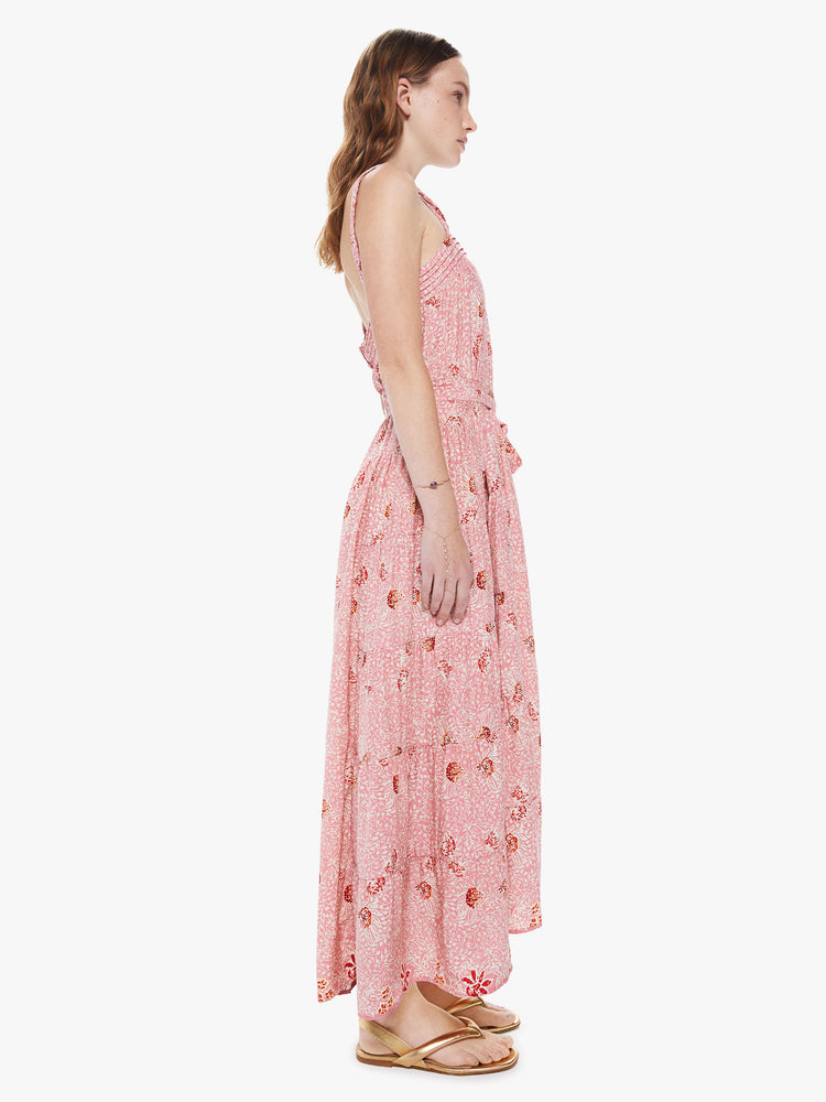 Side view of a woman wearing a pink printed maxi dress featuring a flowy fit and a tie waist.