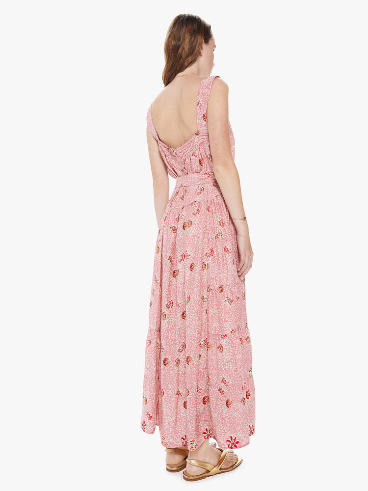 Back view of a woman wearing a pink printed maxi dress featuring a flowy fit and a tie waist.