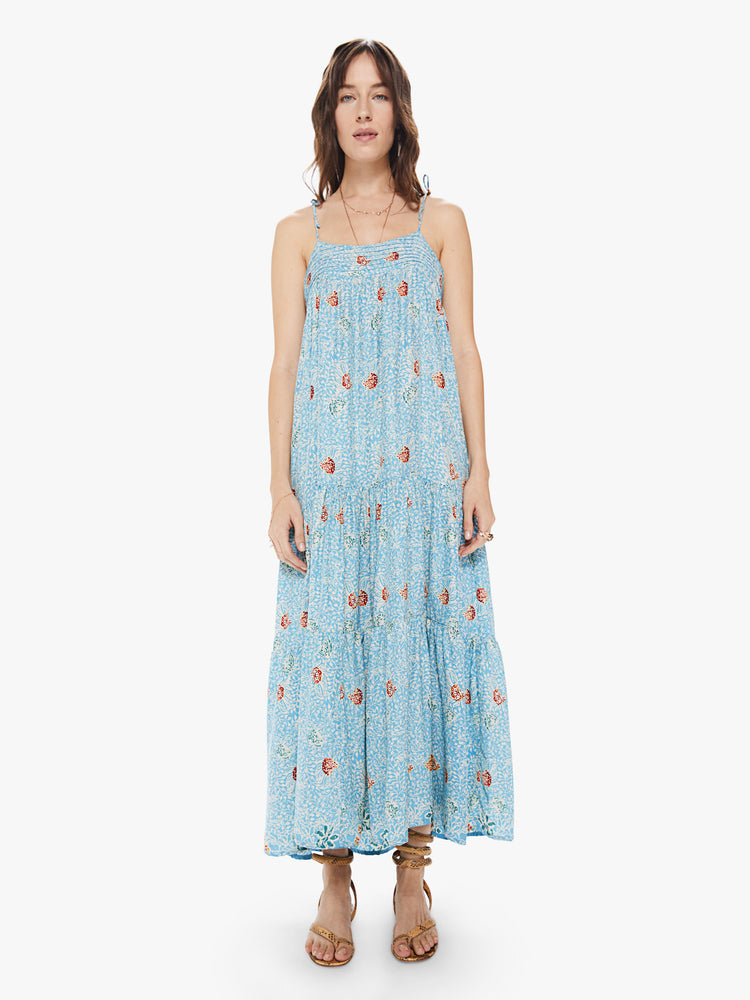 Front view of a women's light blue tiered maxi dress with all-over floral print and spaghetti straps