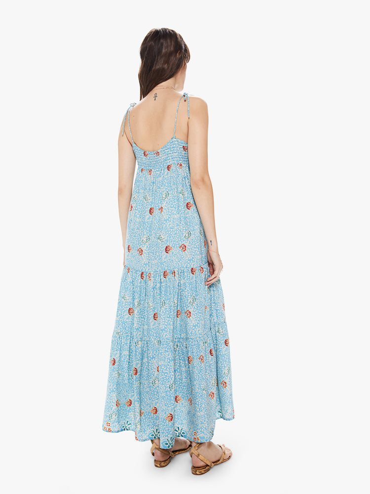 Back view of a women's light blue tiered maxi dress with all-over floral print and spaghetti straps