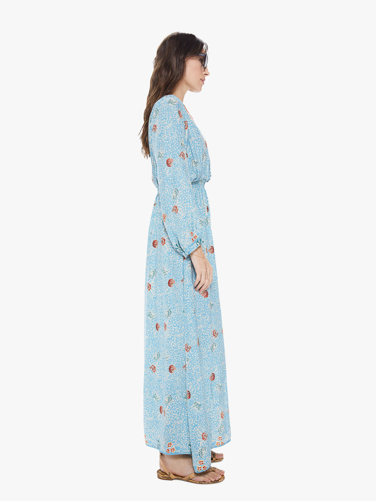 Side view of a women's light  blue maxi dress with all-over floral print and long sleeves