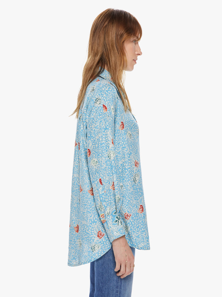 Side view of a women's light blue button front long sleeve shirt with an all over floral print