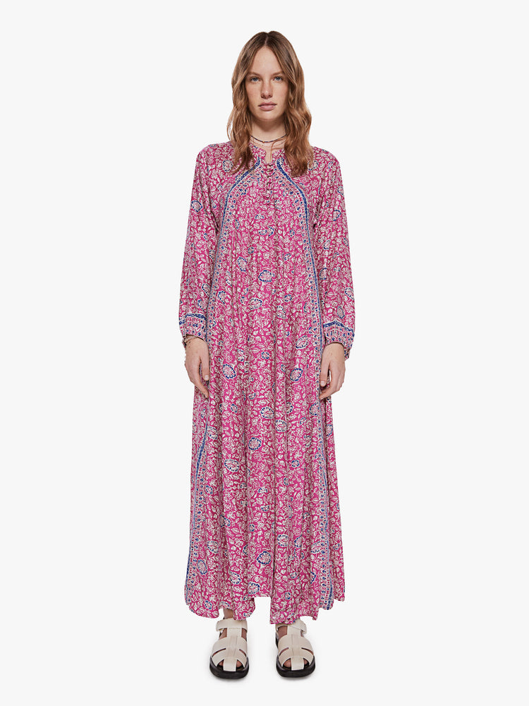 Front view of a woman wearing a pink maxi dress featuring a blue floral print and long sleeves.