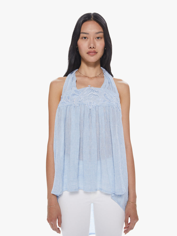 Front view of a woman wearing a sheer light blue linen halter top featuring a loose flowy fit and lace trim.
