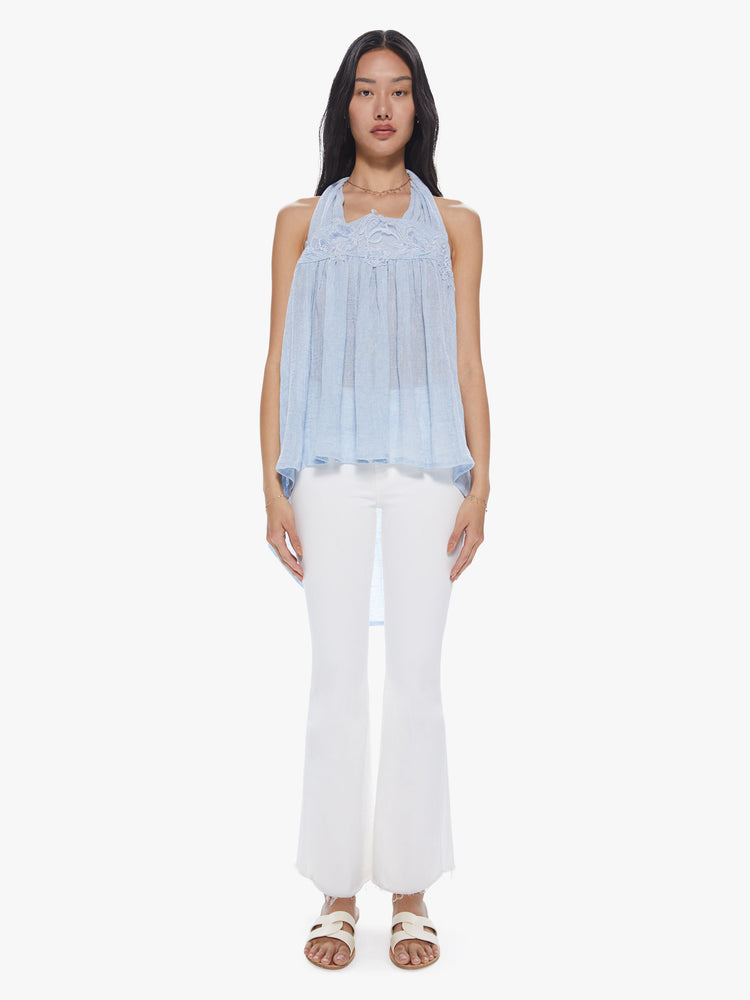 Front front full view of a woman wearing a sheer light blue linen halter top featuring a loose flowy fit and lace trim.