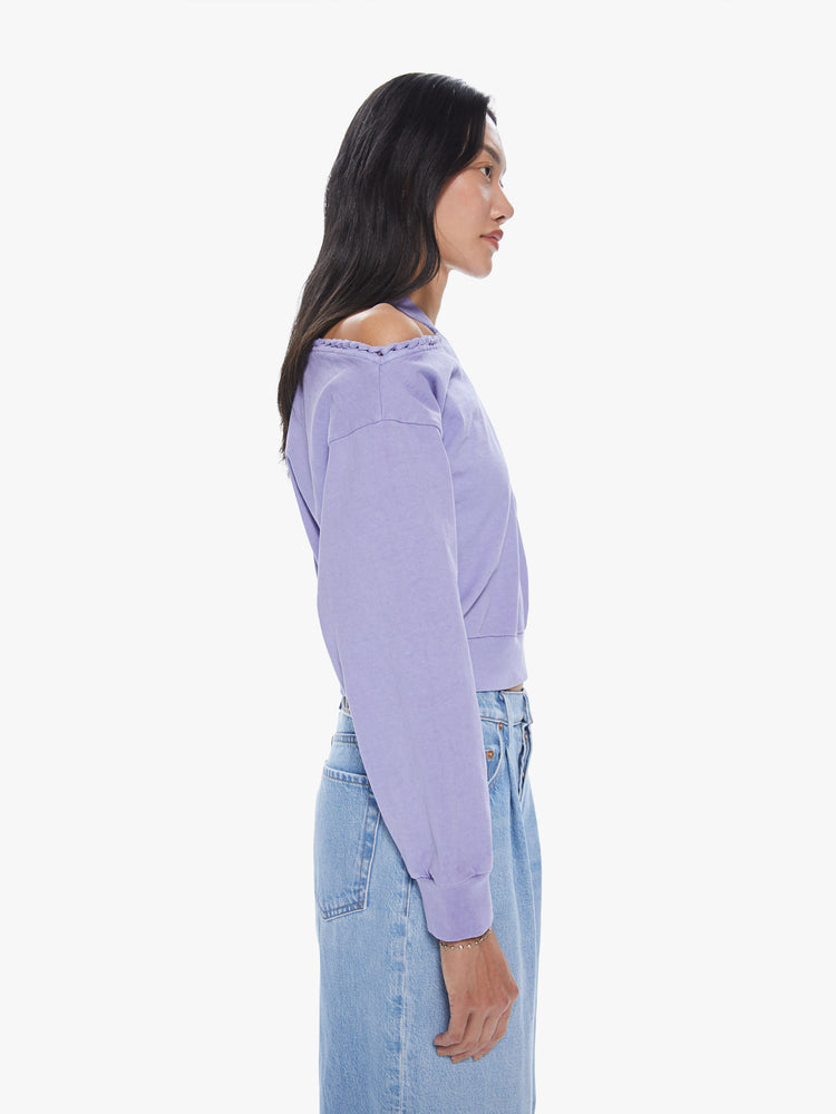 Side view of a woman wearing a cropped lavender pullover featuring dropped sleeves and cut-out shoulders.