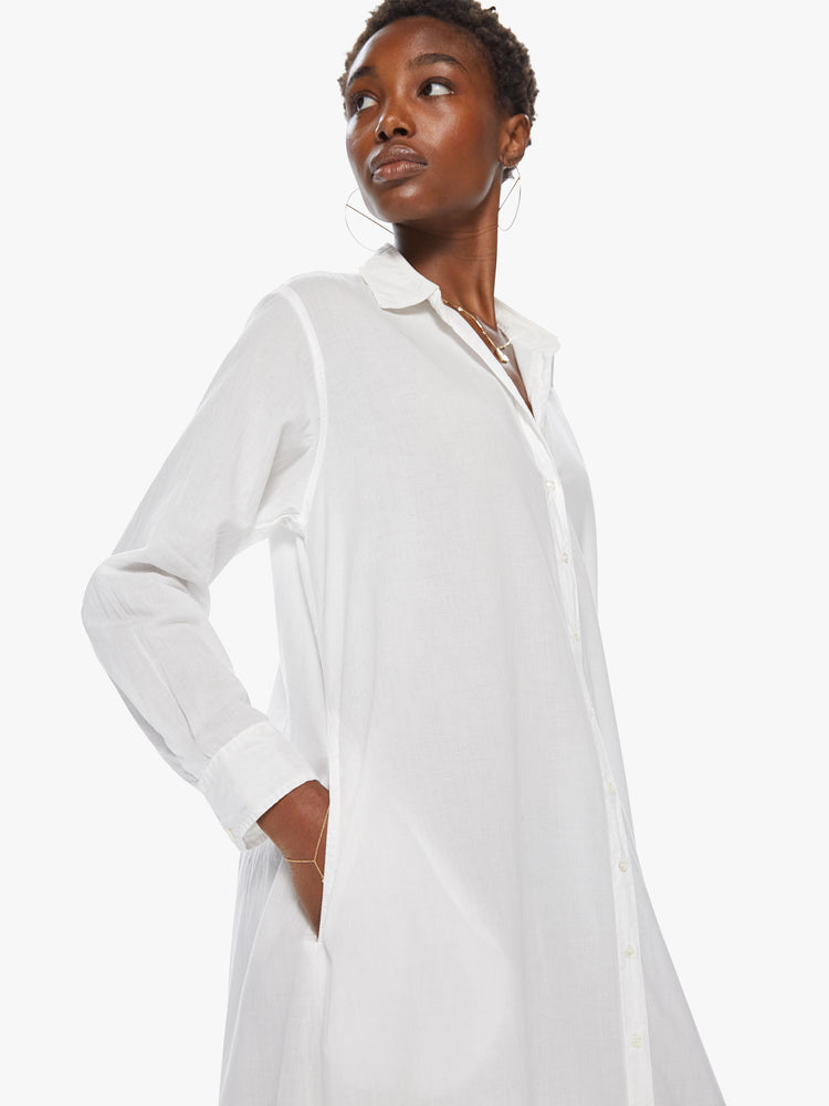 Side detail view of a women's long white collared shirt dress with long sleeves