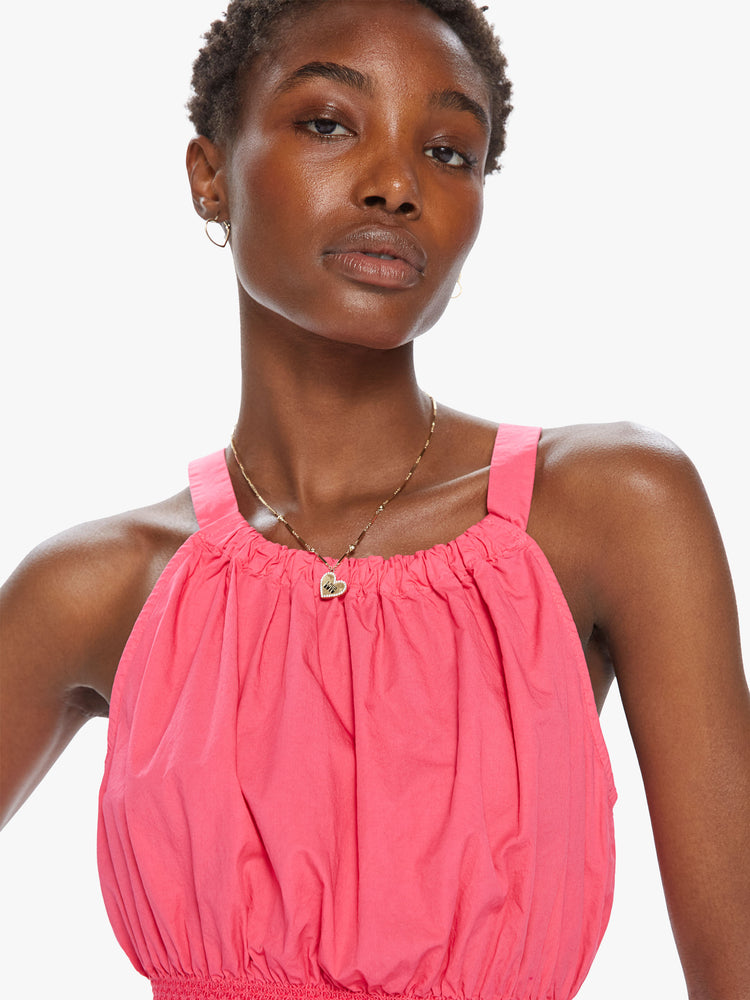 Front detail view of a women's bright pink crop top with halter straps and a smocked waist