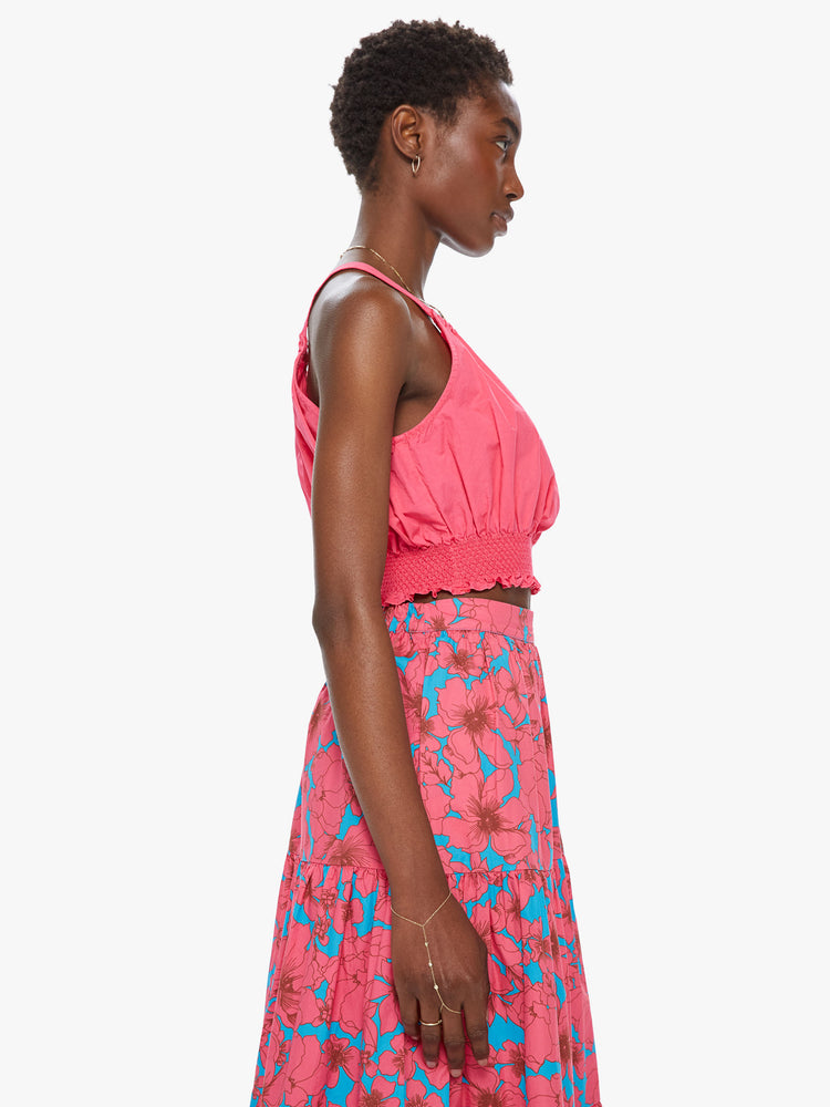 Side view of a women's bright pink crop top with halter straps and a smocked waist