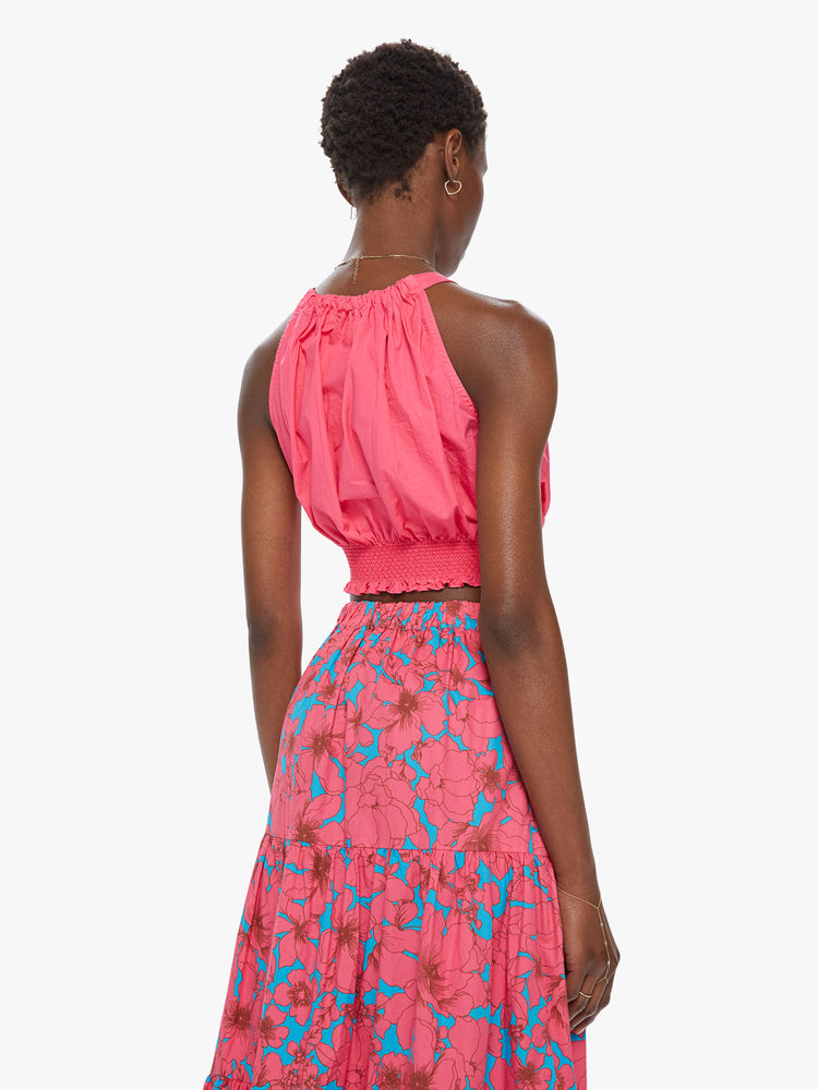 Back view of a women's bright pink crop top with halter straps and a smocked waist