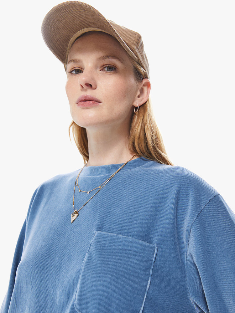 Front close up view of a women's long sleeve crew neck tee featuring a blue faded ribbed fabric, dropped sleeves, a chest pocket, and an oversized fit.