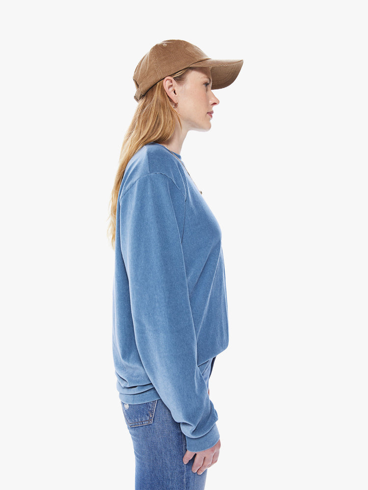 Side view of a women's long sleeve crew neck tee featuring a blue faded ribbed fabric, dropped sleeves, a chest pocket, and an oversized fit.