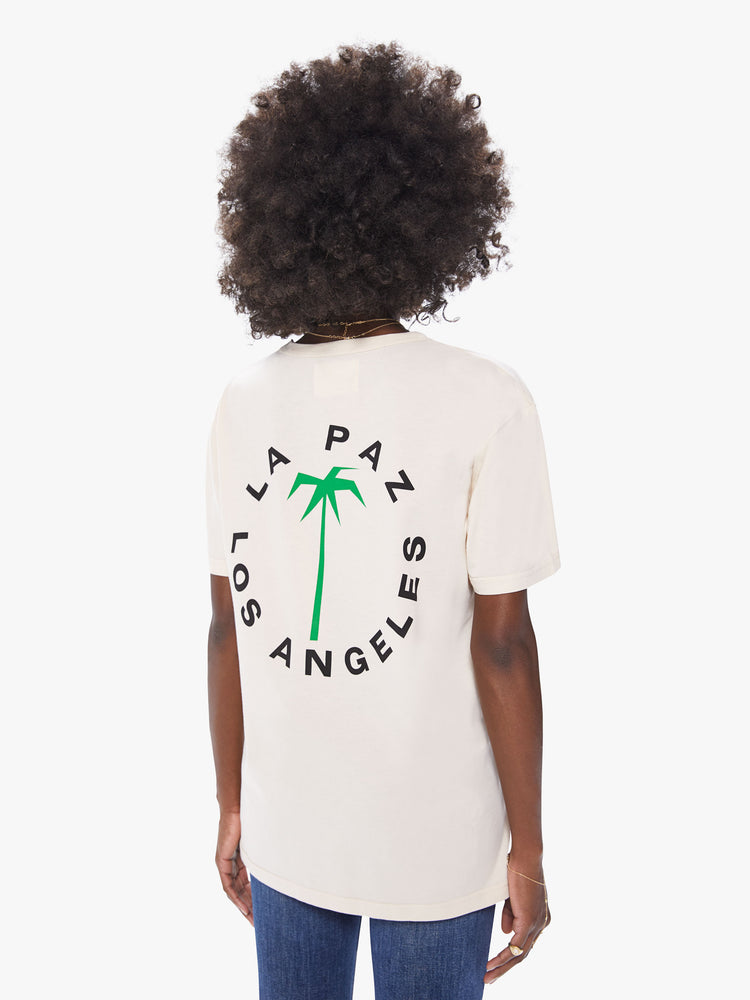 Back view of a women's ecru crew neck tee featuring a large back graphic of a palm tree and "LA PAZ LOS ANGELES" and an oversized fit.