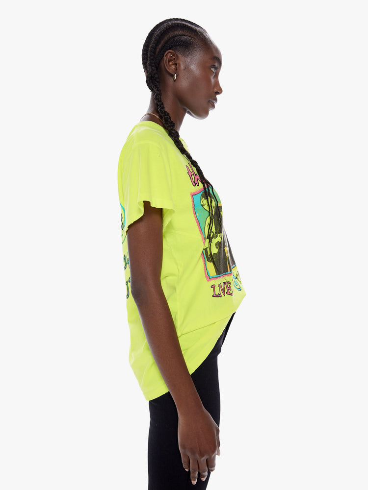 Side view of a woman wearing a neon crew neck tee featuring a large B-52's concert graphic and an oversized fit.