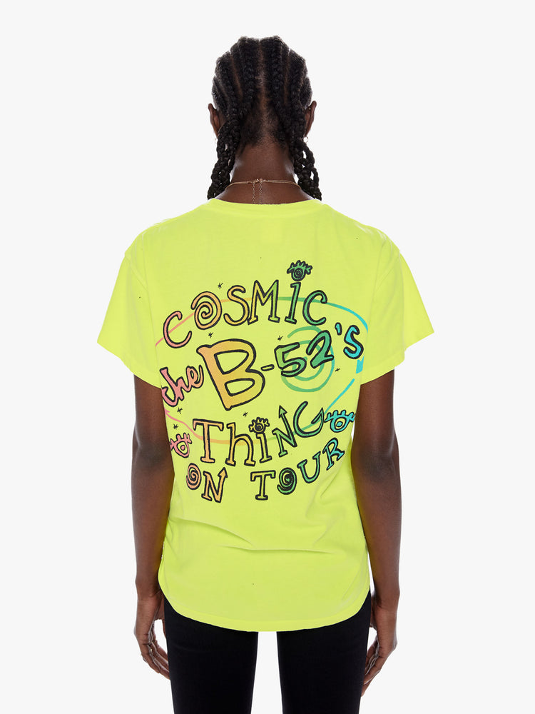 Back view of a woman wearing a neon crew neck tee featuring a large B-52's concert graphic and an oversized fit.