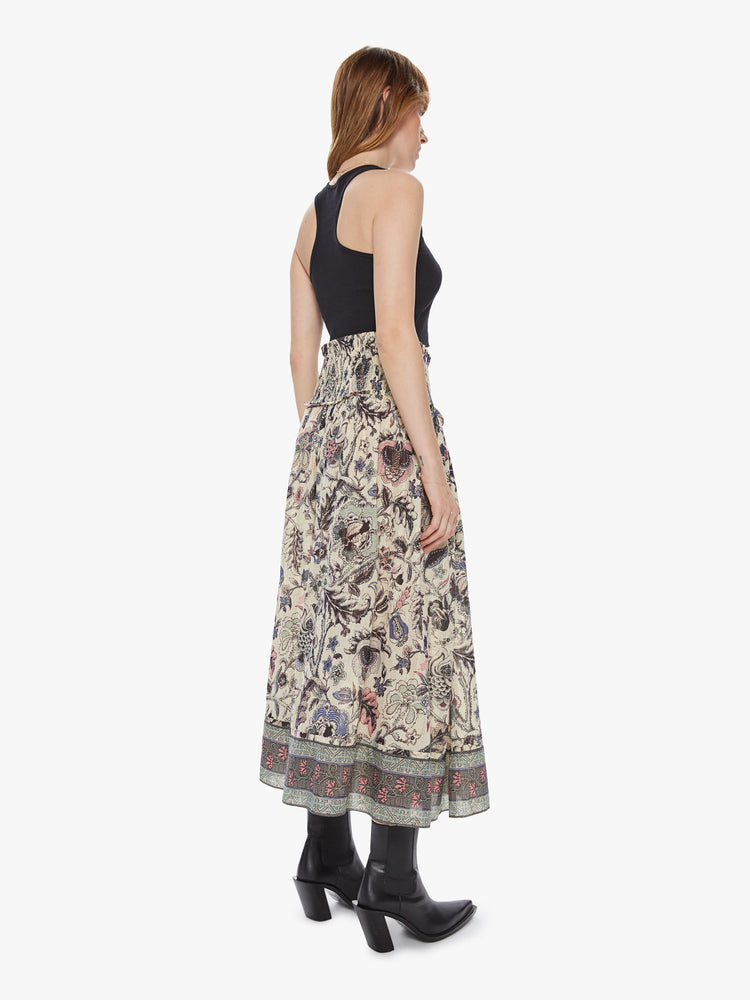 Back view of a woman wearing a long floral print skirt featuring a high rise elastic waist.