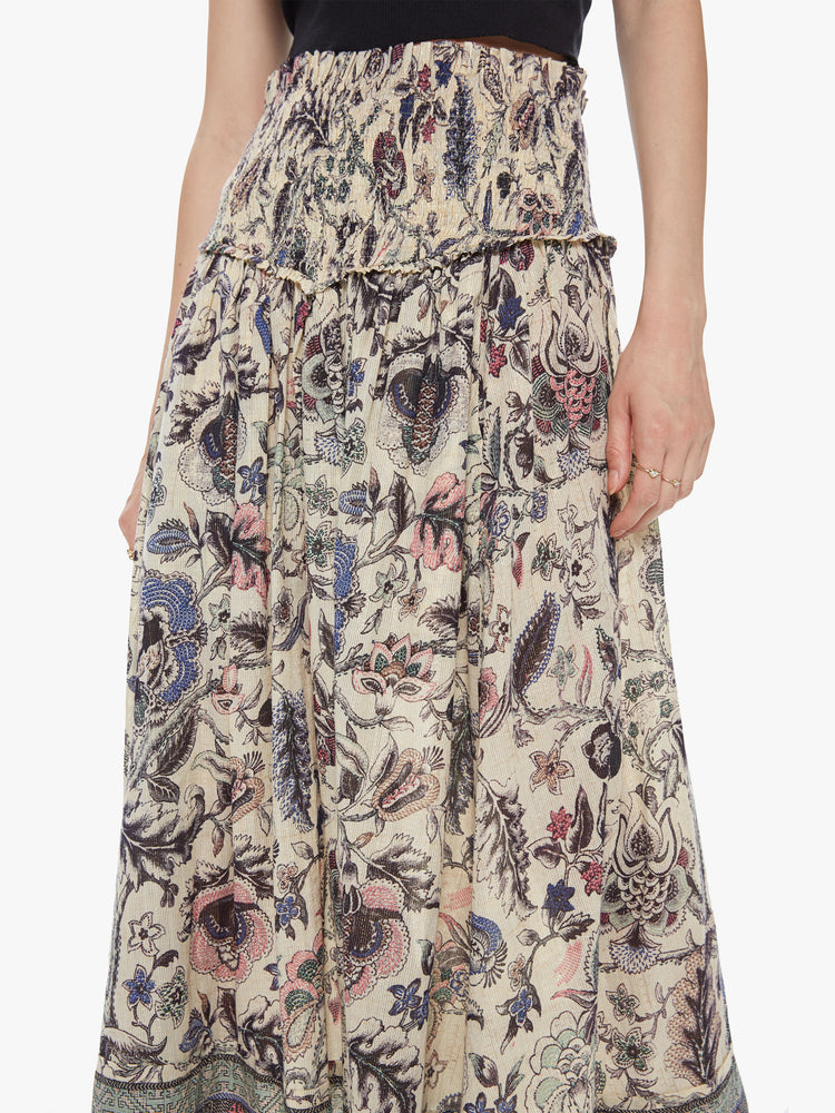 Front close up view of a woman wearing a long floral print skirt featuring a high rise elastic waist.