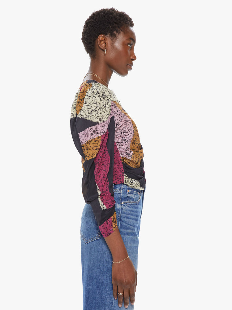 Side view of a woman wearing a long sleeve top featuring a textured colorblock print, a cropped body, puff sleeves, and rouched seams throughout.