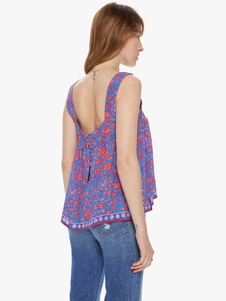 Back view of a woman wearing a sleeveless top featuring a slightly cropped body, thick straps, buttons on the back and a blue and pink floral print.