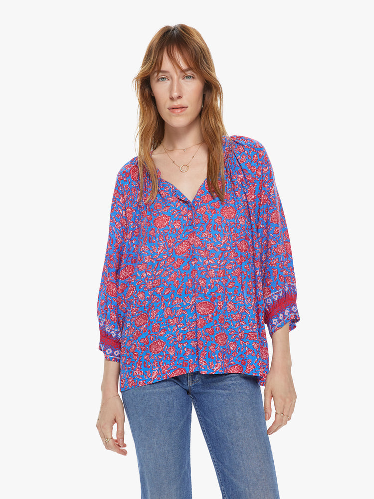 Front view of a woman wearing a flowy button down top featuring 3/4 length sleeves and a blue and pink floral print.
